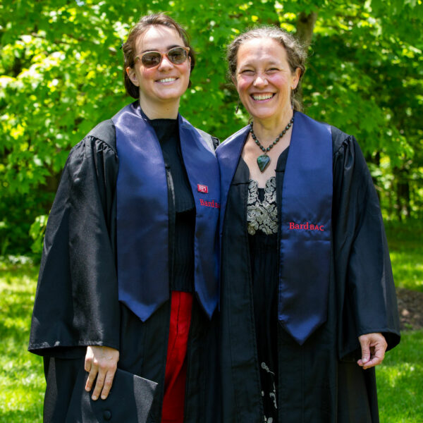 Two smiling BardBac students in graduation regalia.