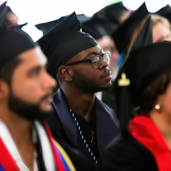 BardBac graduate listening intently at commencement.